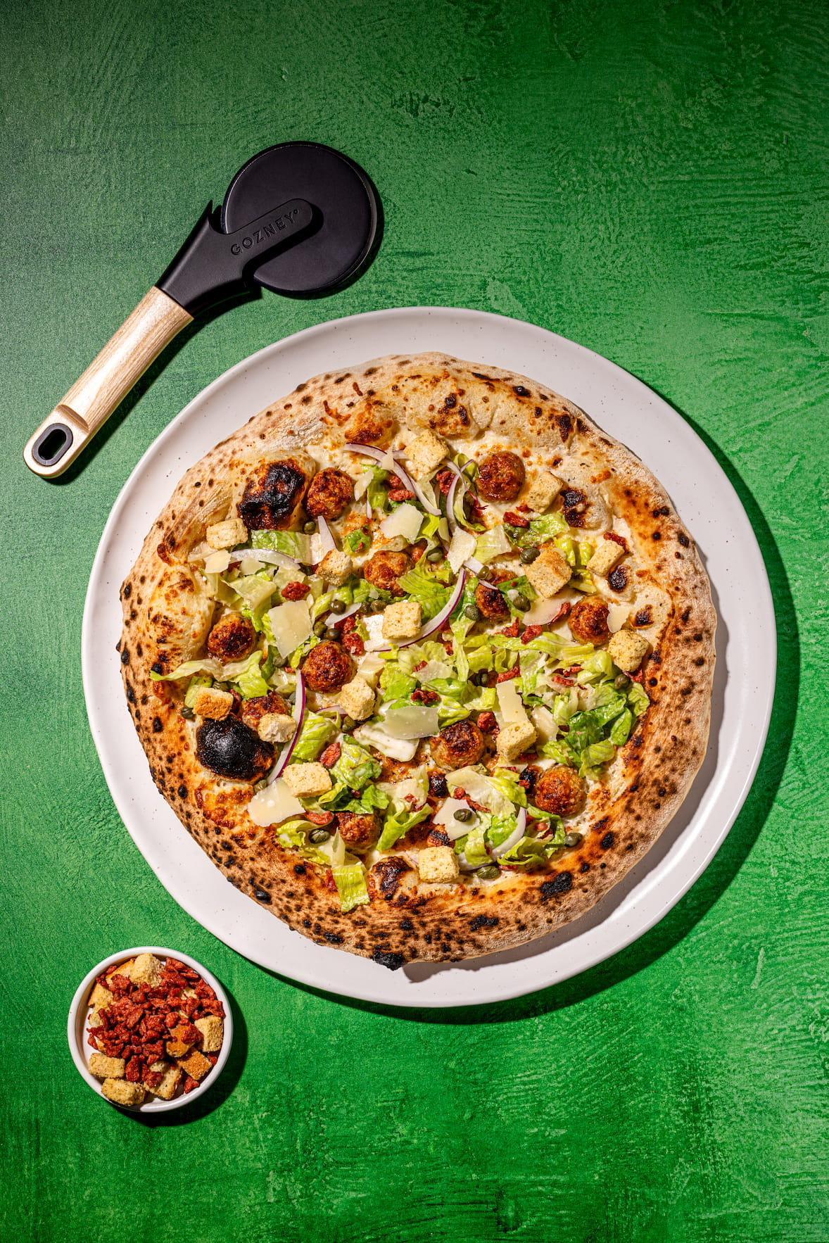 Pizzas César aux boulettes de poulet maison garnies de laitue romaine, croûtons et parmesan