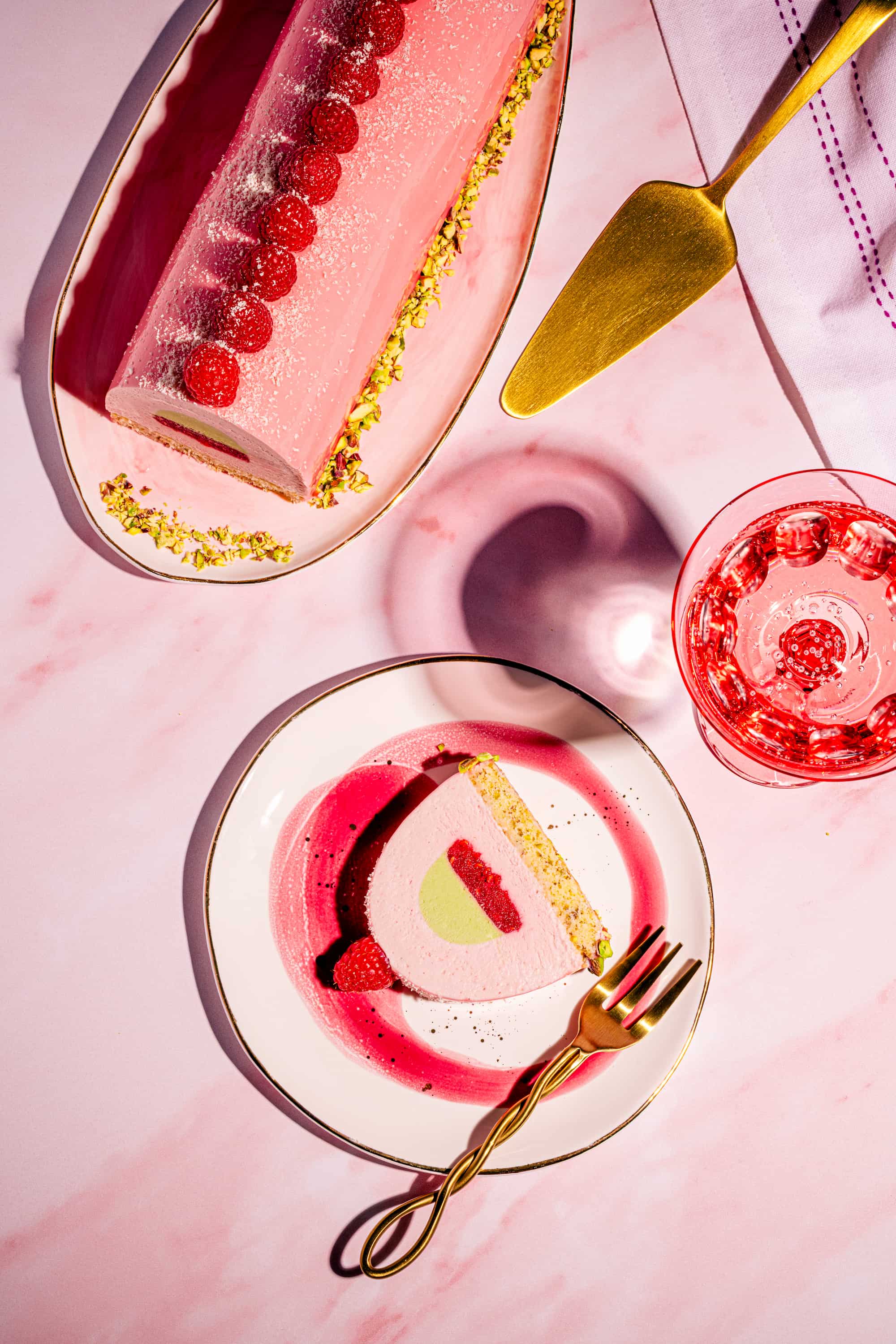 Bûche aux framboises et aux pistaches avec glaçage miroir au chocolat blanc