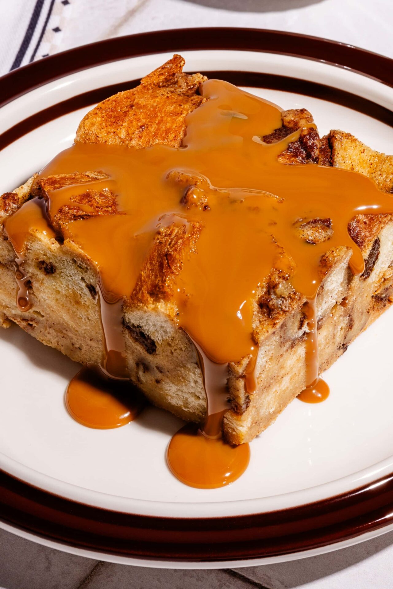 Pouding de pain perdu cannelle et raisins nappé de dulce de leche dans une assiette