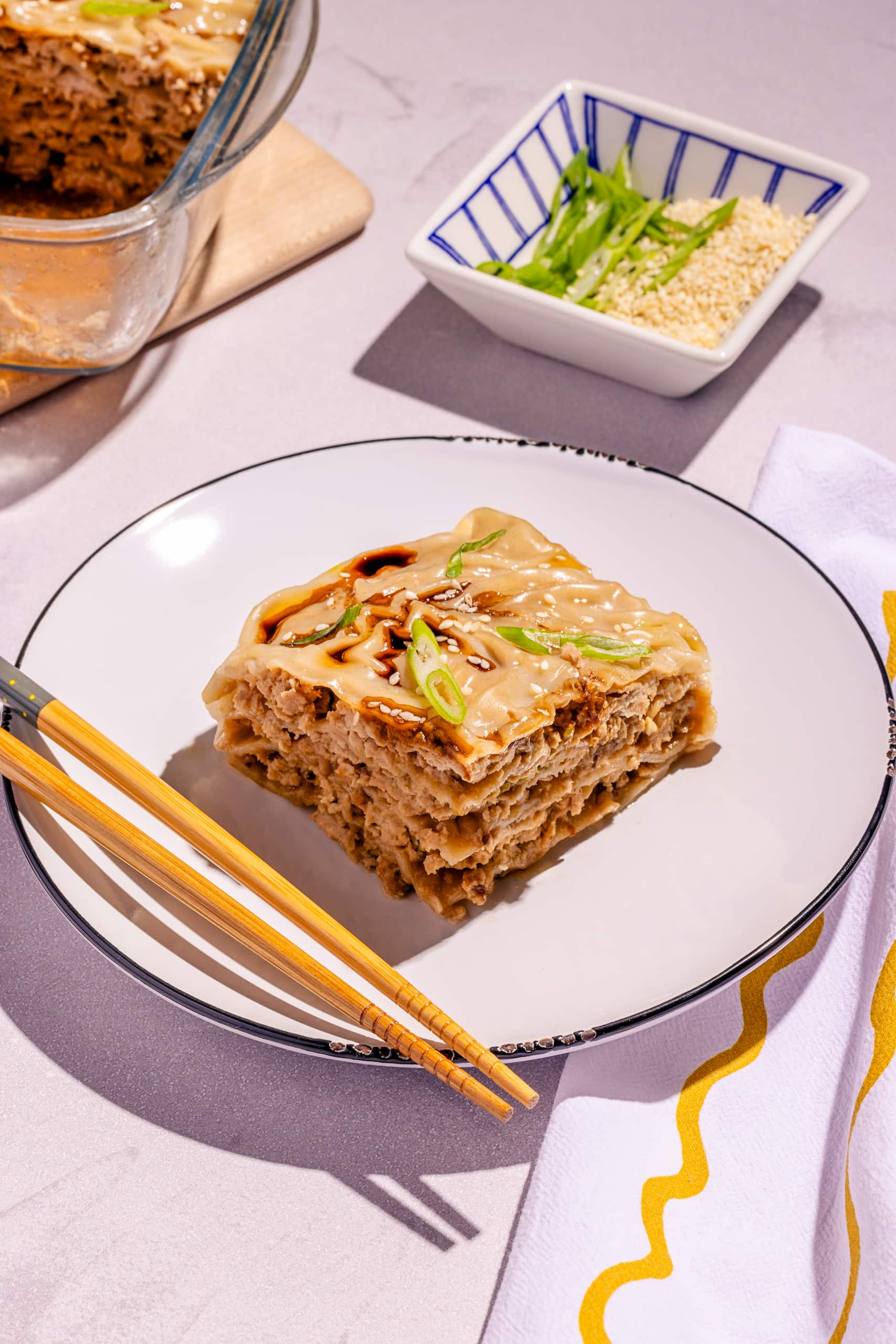 Lasagne dumpling au porc à la vapeur garnie d’oignon vert et sésame