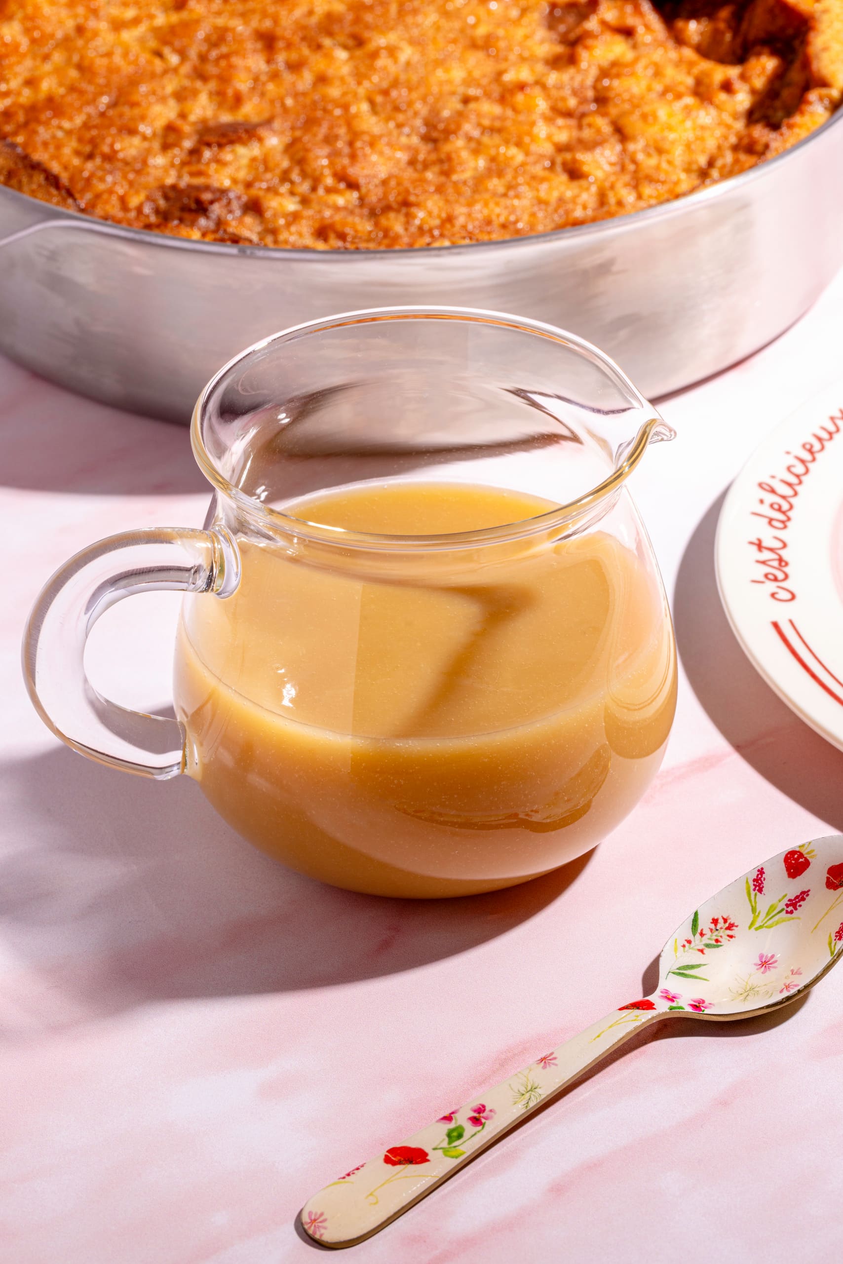 Sauce crémeuse au sirop d'érable versée sur un pouding au pain