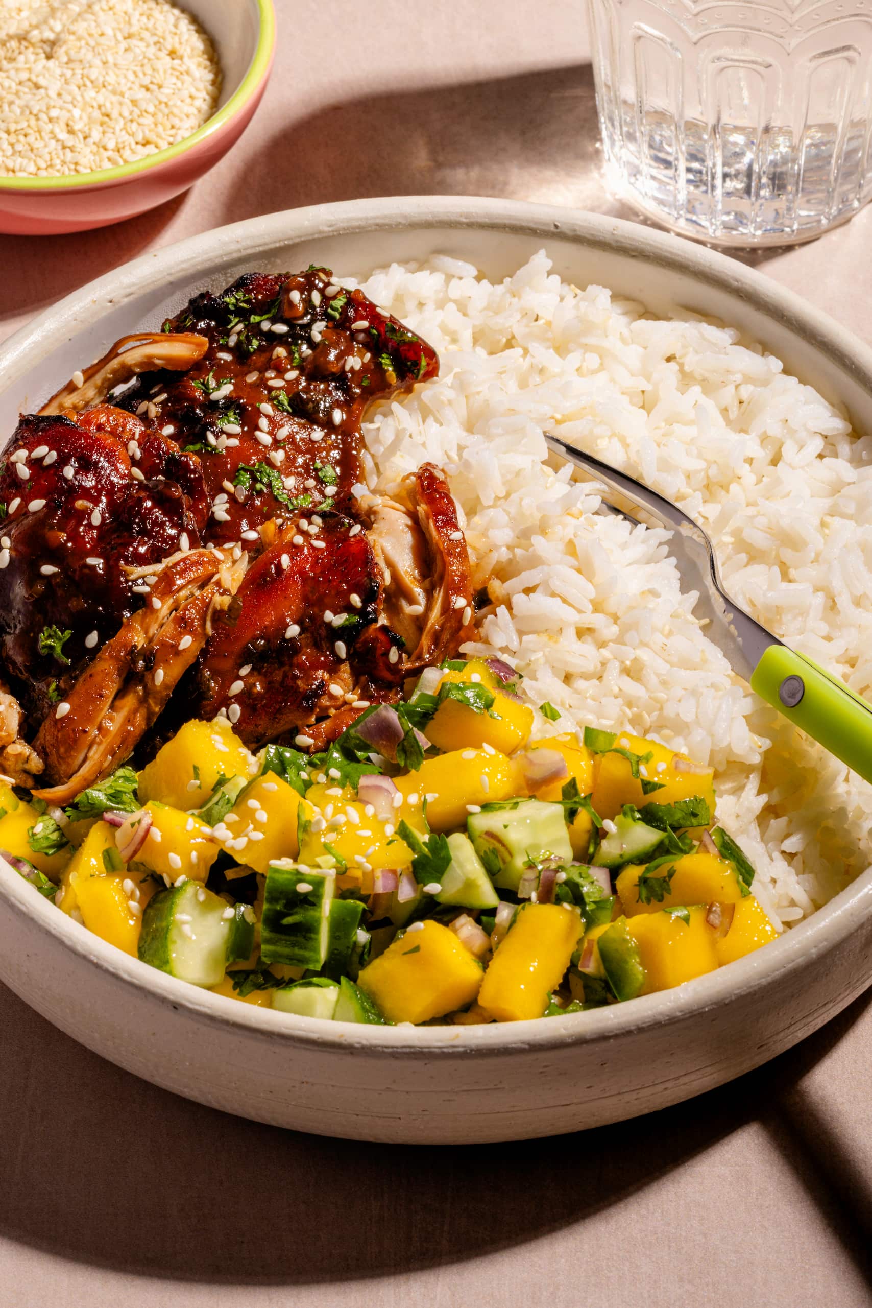 Bol de hauts de cuisses à l'asiatique garni de salsa de mangues et servi sur riz