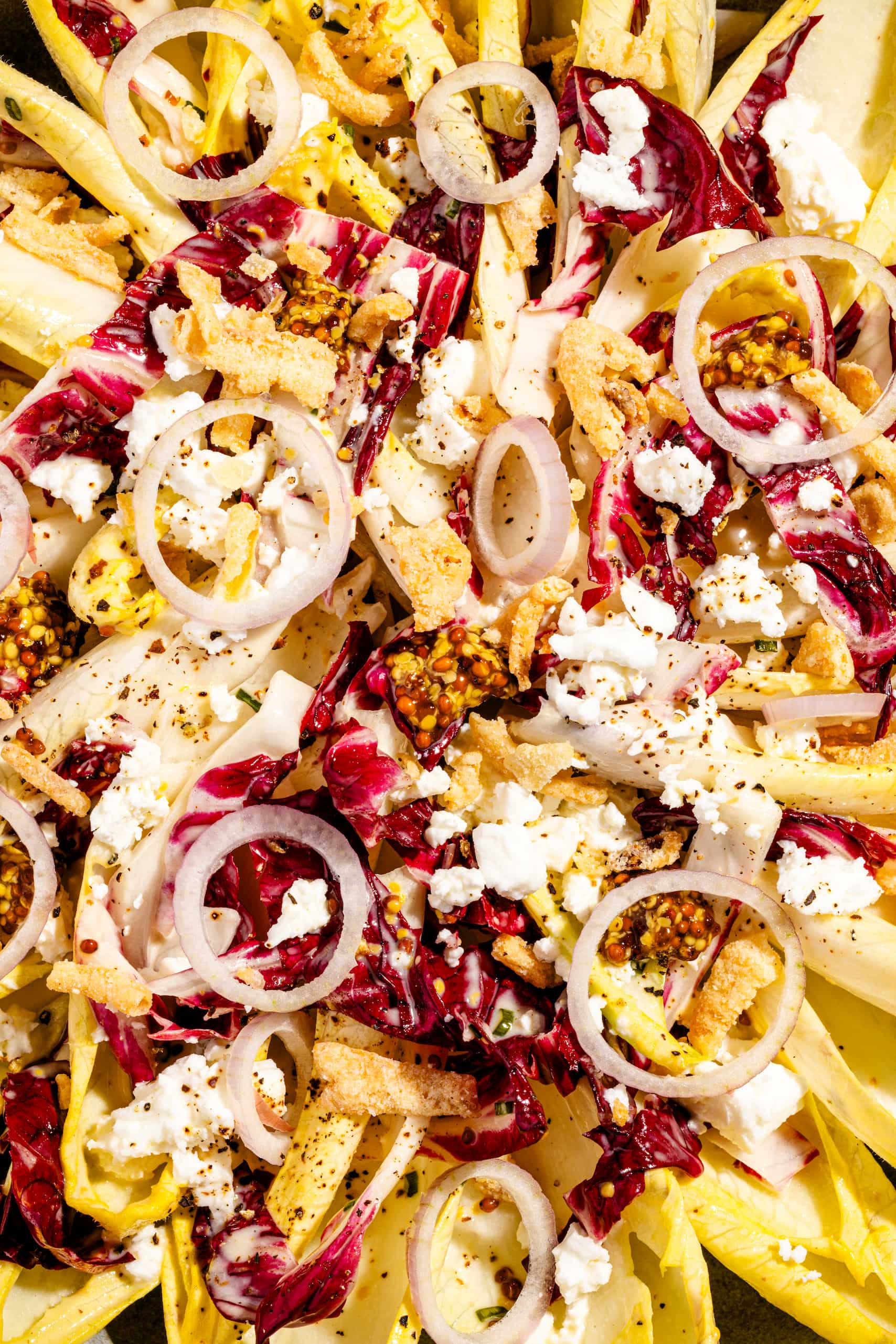 Salade d'endives estivale garnie de feta, d'oignons frits et de vinaigrette à l'érable