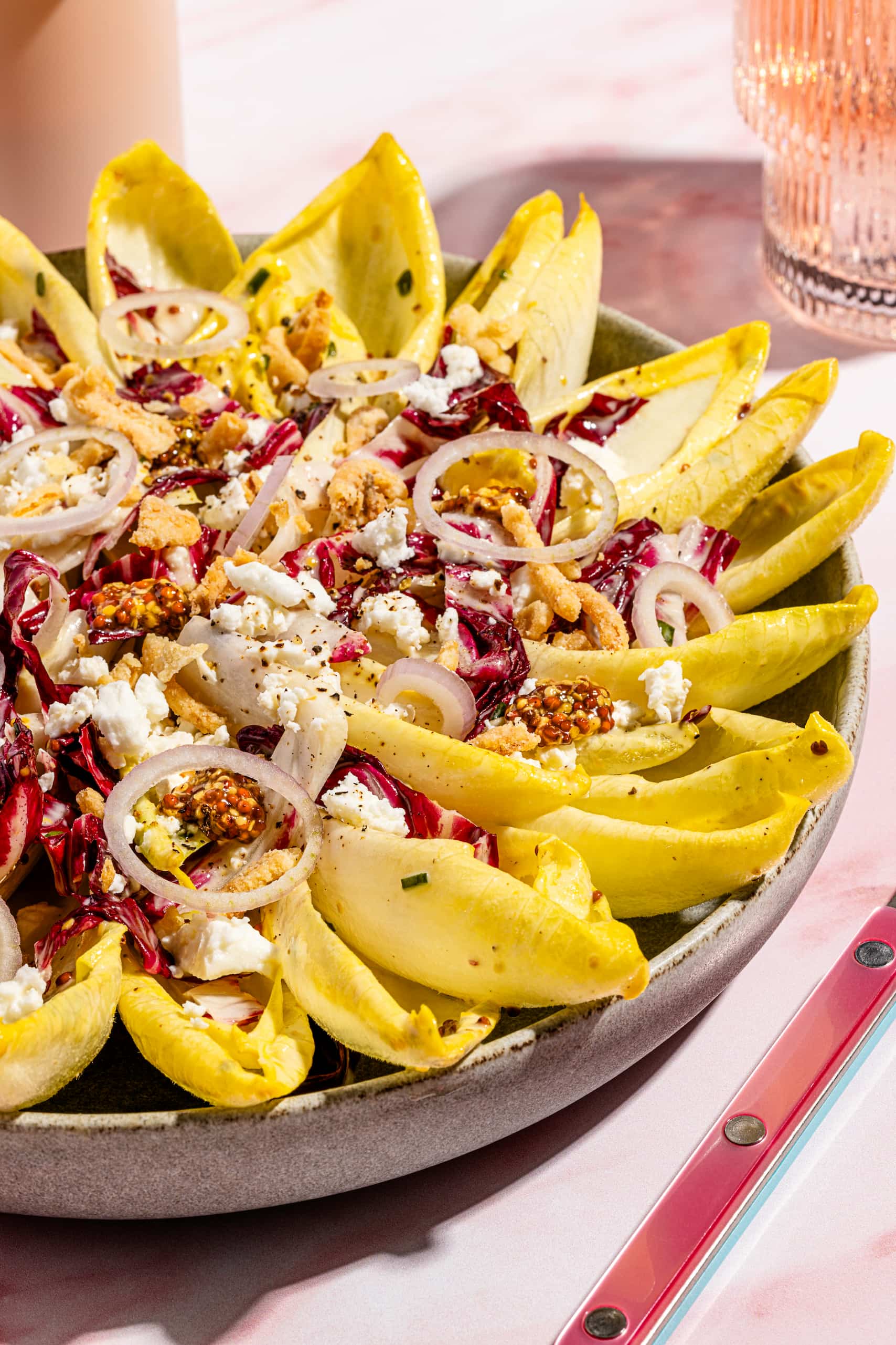 Salade d'endives estivale garnie de feta, d'oignons frits et de vinaigrette à l'érable