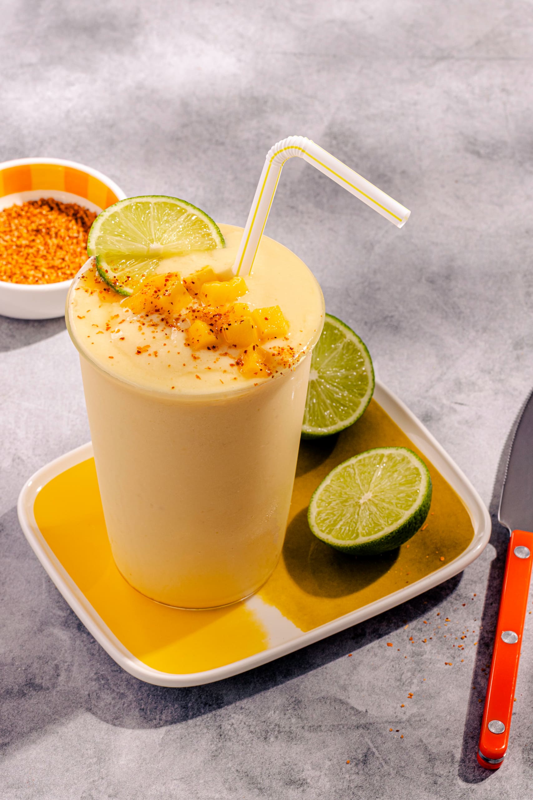 Smoothie mangue ananas crémeux garni de Tajin et d'un quartier de lime fraîche