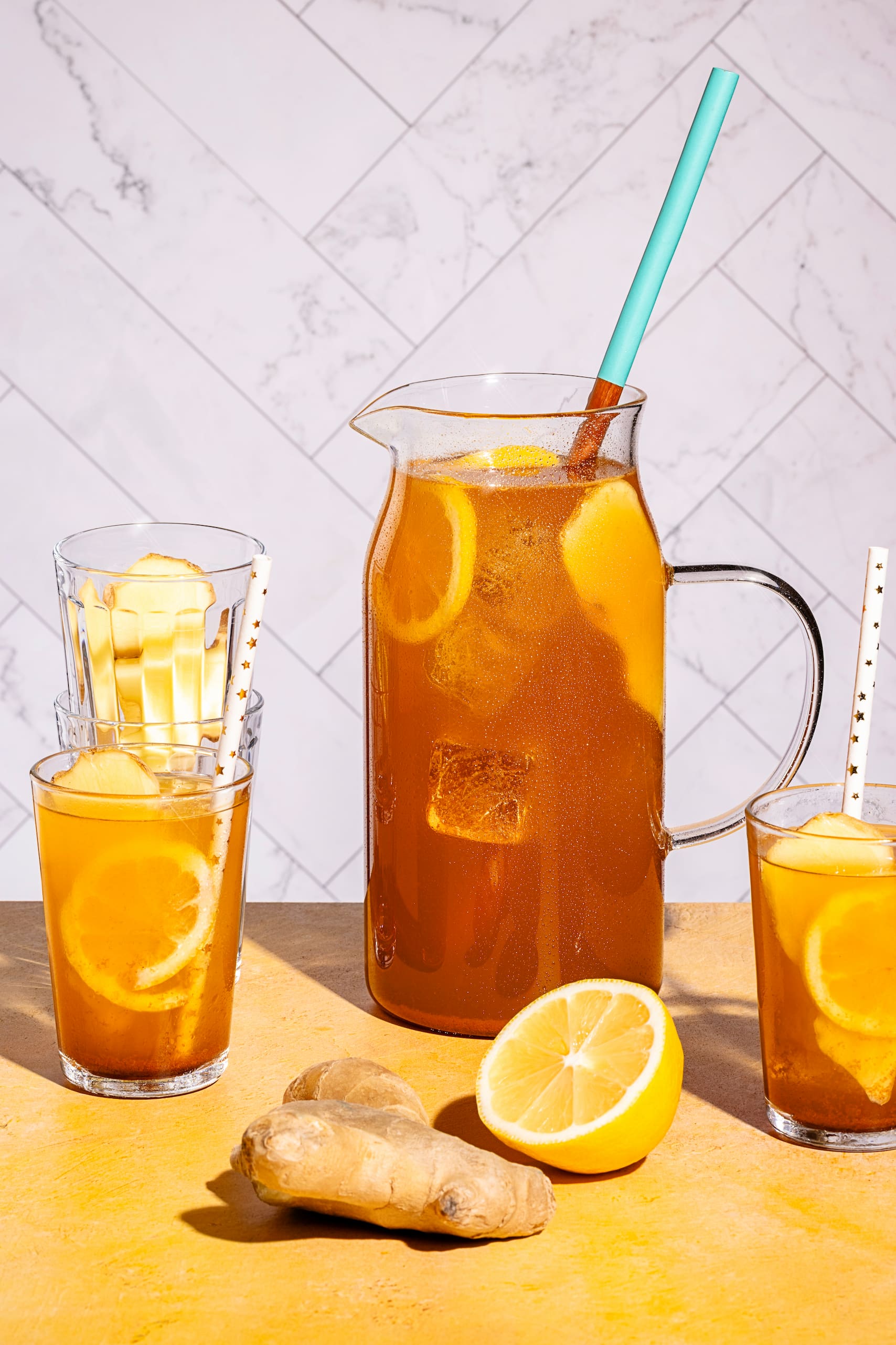 Thé glacé chaï maison servi dans un grand verre avec glaçons, citron et gingembre frais