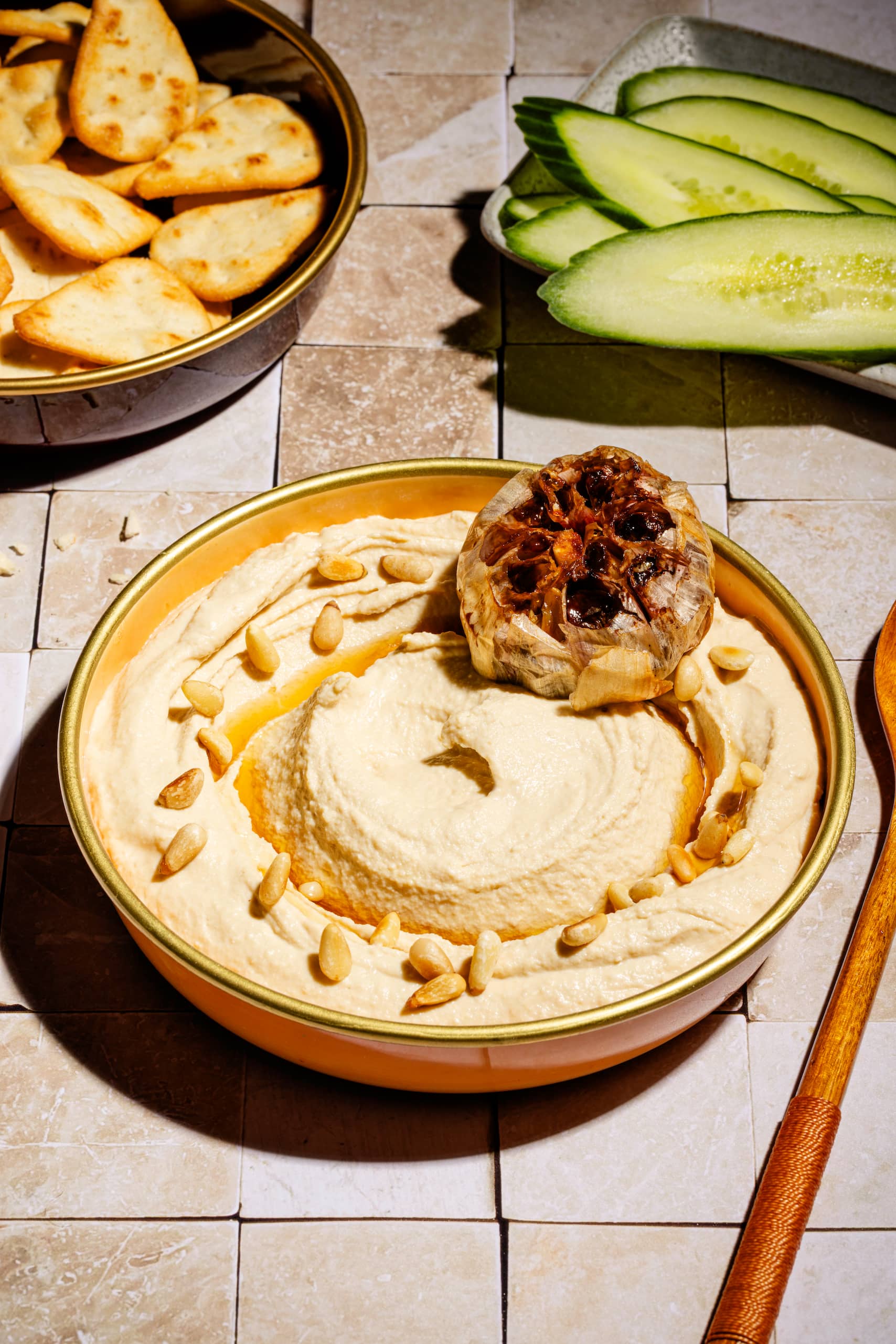 Houmous à l'ail rôti maison crémeux servi avec huile d'olive et pignons grillés