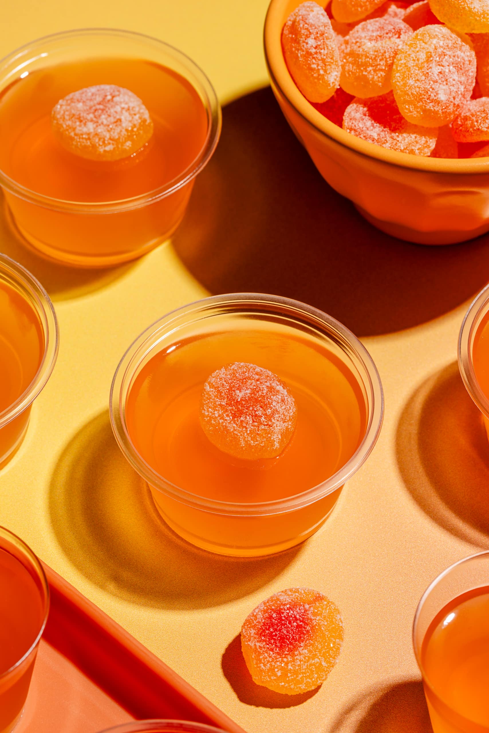 Shots gélifiés à la pêche servis dans des verres à shooter avec bonbons