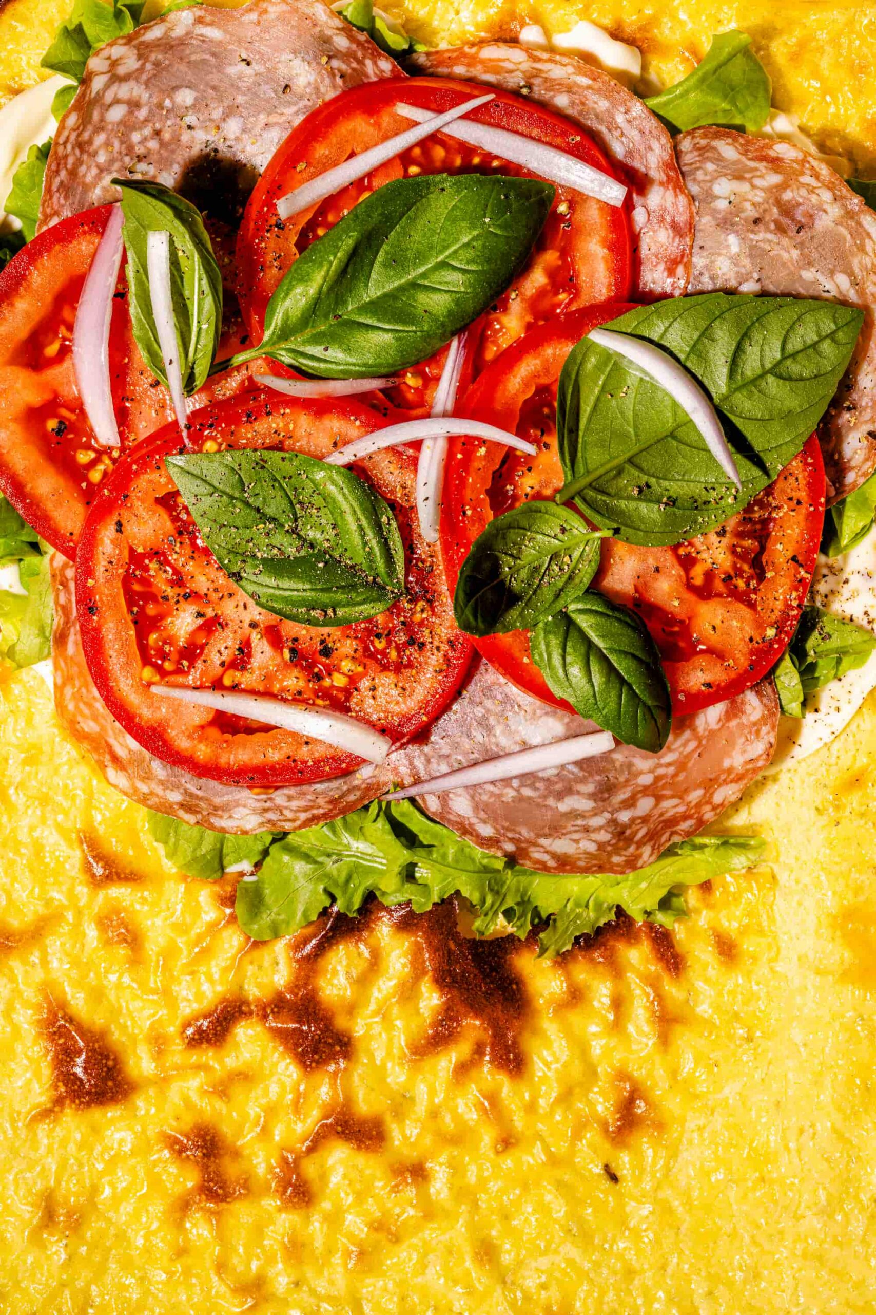 Pains plats protéinés au fromage cottage garnis de tomates fraîches, de viandes froides et de basilic