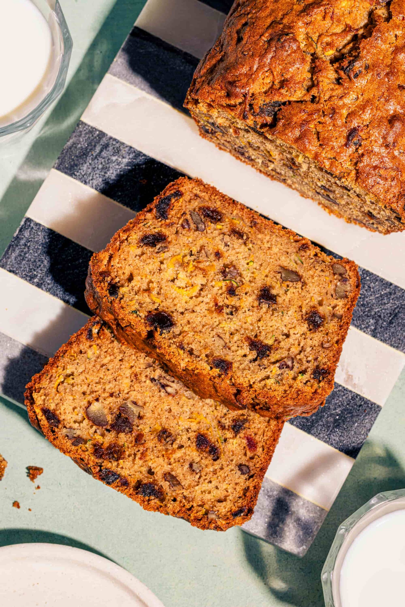 Tranches de pain aux courgettes et aux dattes garnies de pacanes sur planche de marbre