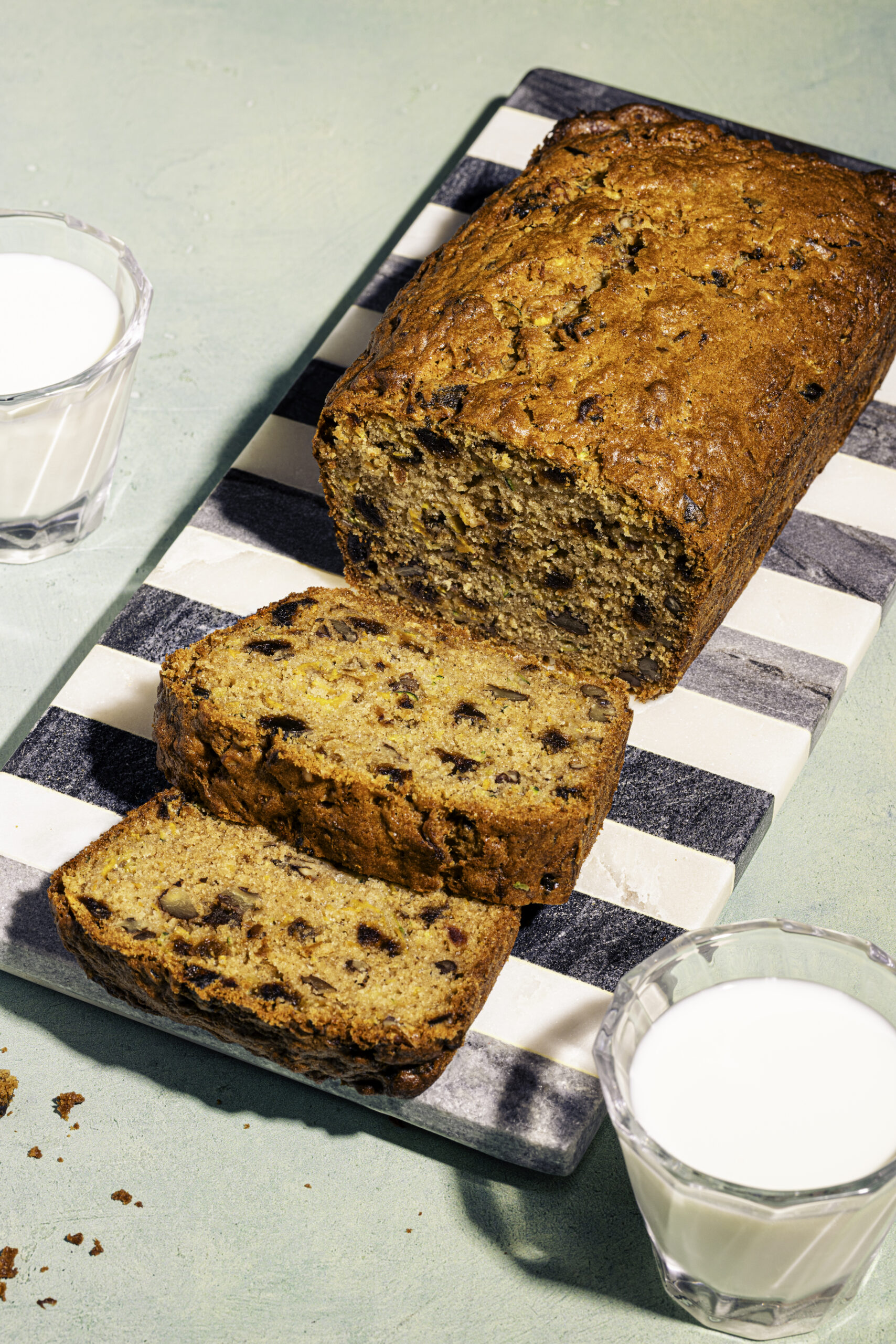 Tranches de pain aux courgettes et aux dattes garnies de pacanes sur planche de marbre