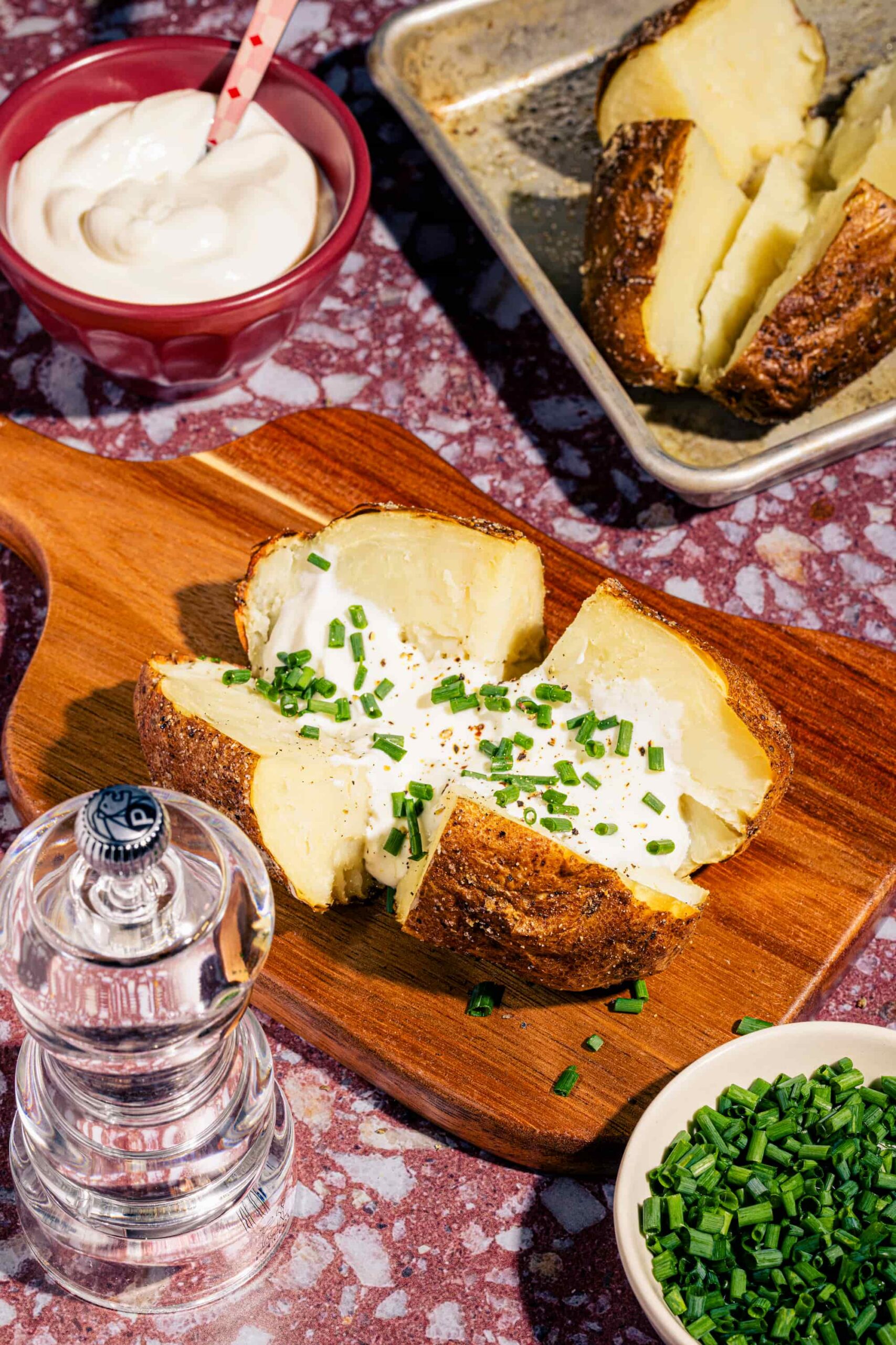 Pomme de terre au four croustillante coupée en deux garnie de crème sure et de ciboulette