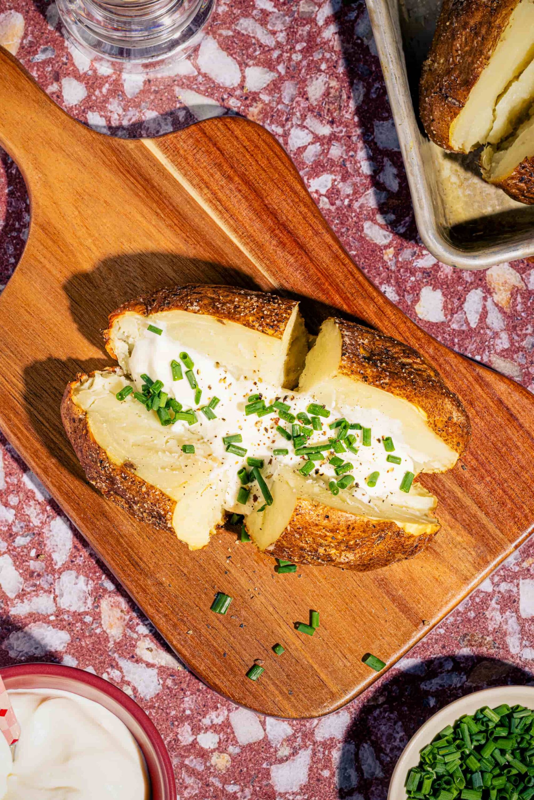 Pomme de terre au four croustillante coupée en deux garnie de crème sure et de ciboulette