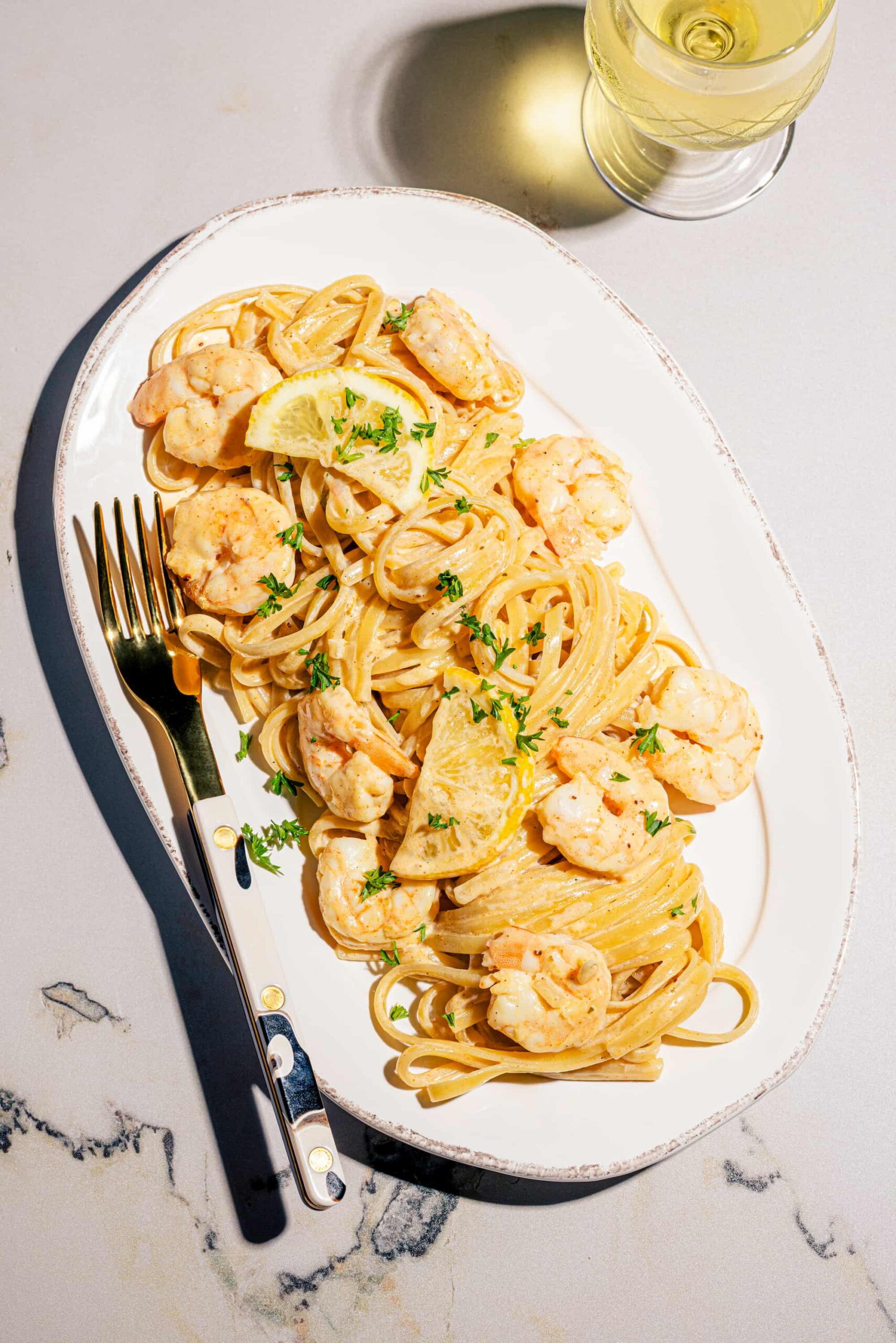 Linguines crémeuses aux crevettes et au parmesan garnies de persil frais dans une assiette