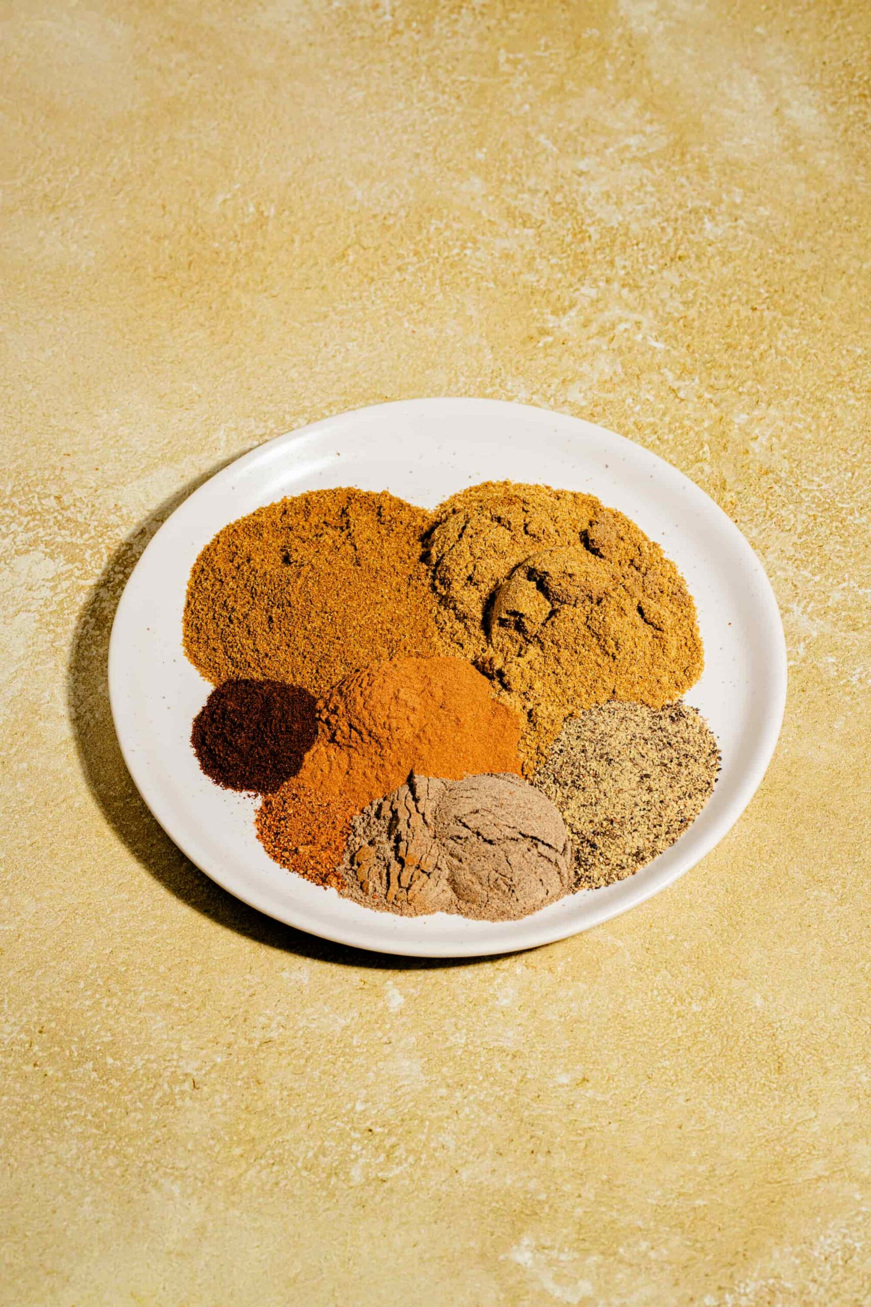 Garam masala maison dans une assiette avec les épices moulues utilisées pour le préparer