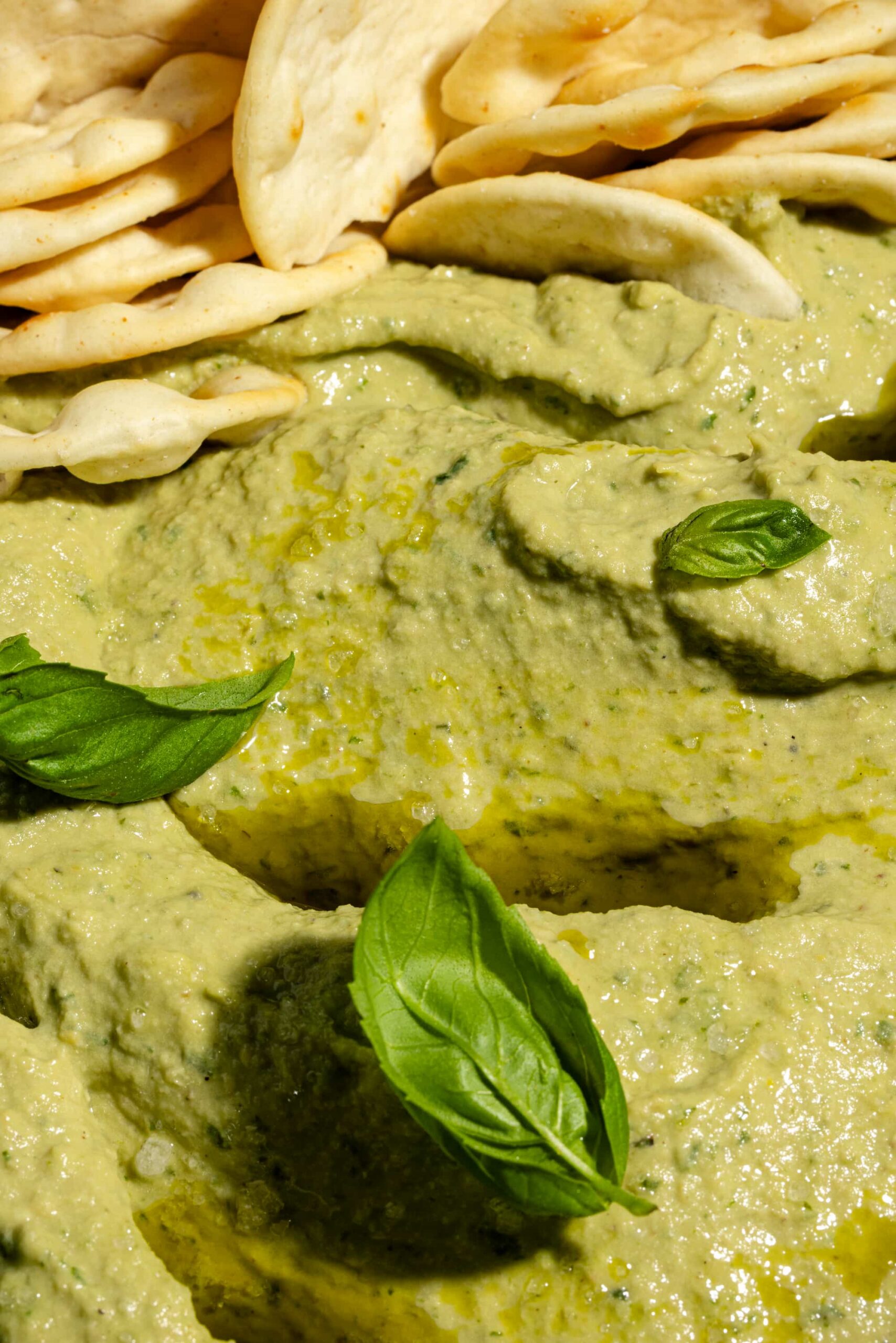 Houmous au basilic ultra crémeux servi dans un bol avec huile d'olive et pita