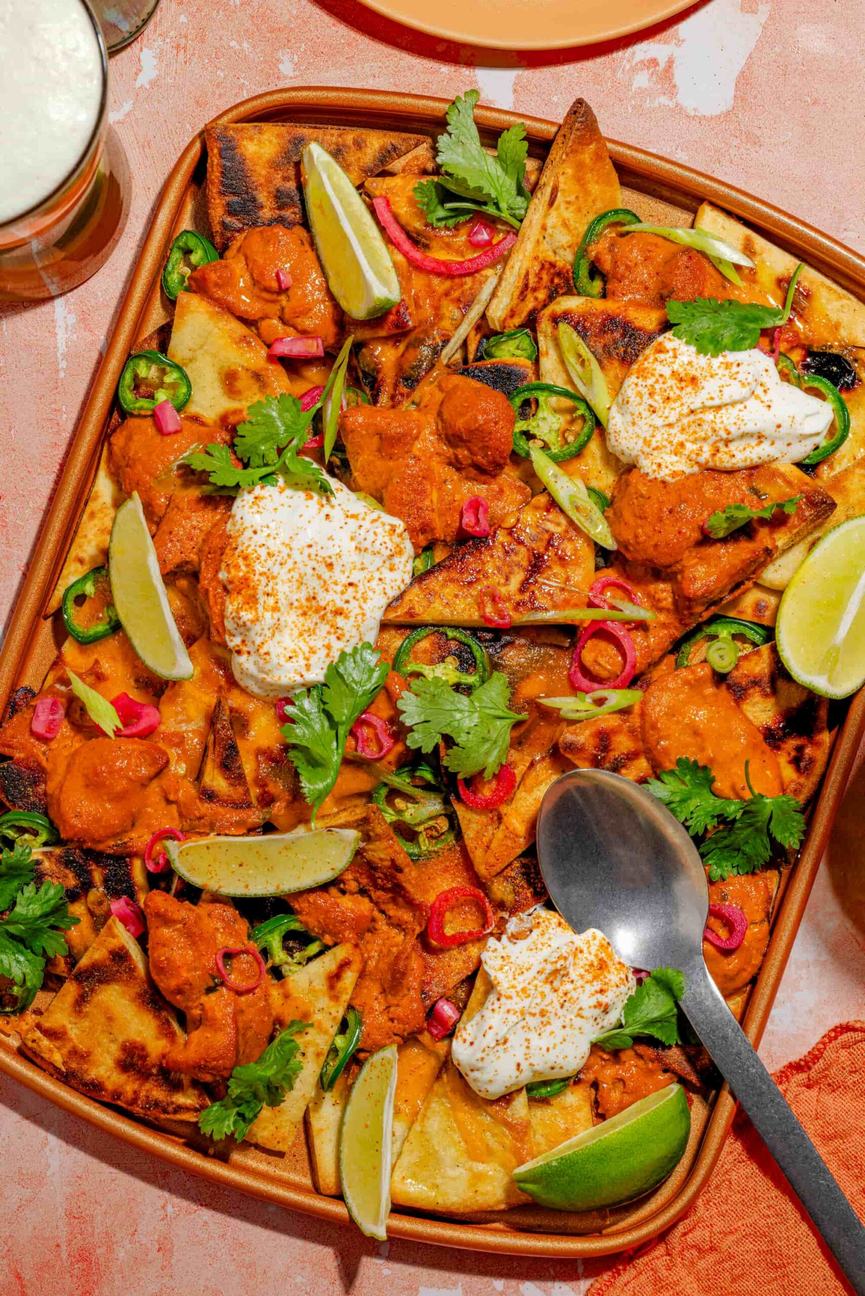 Nachos au poulet au beurre sur pains naan garnis de cheddar fondant et coriandre fraîche