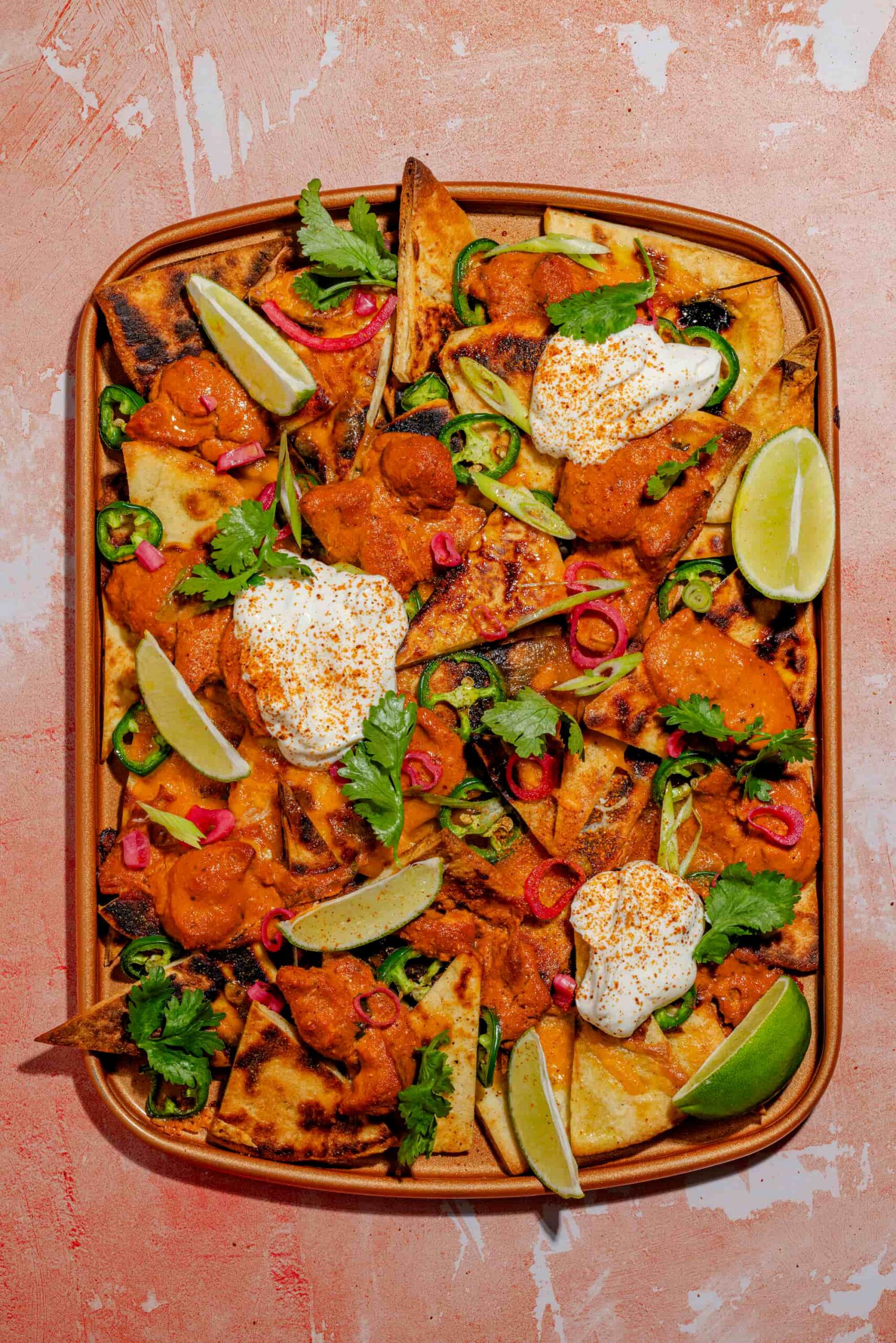 Nachos au poulet au beurre sur pains naan garnis de cheddar fondant et coriandre fraîche