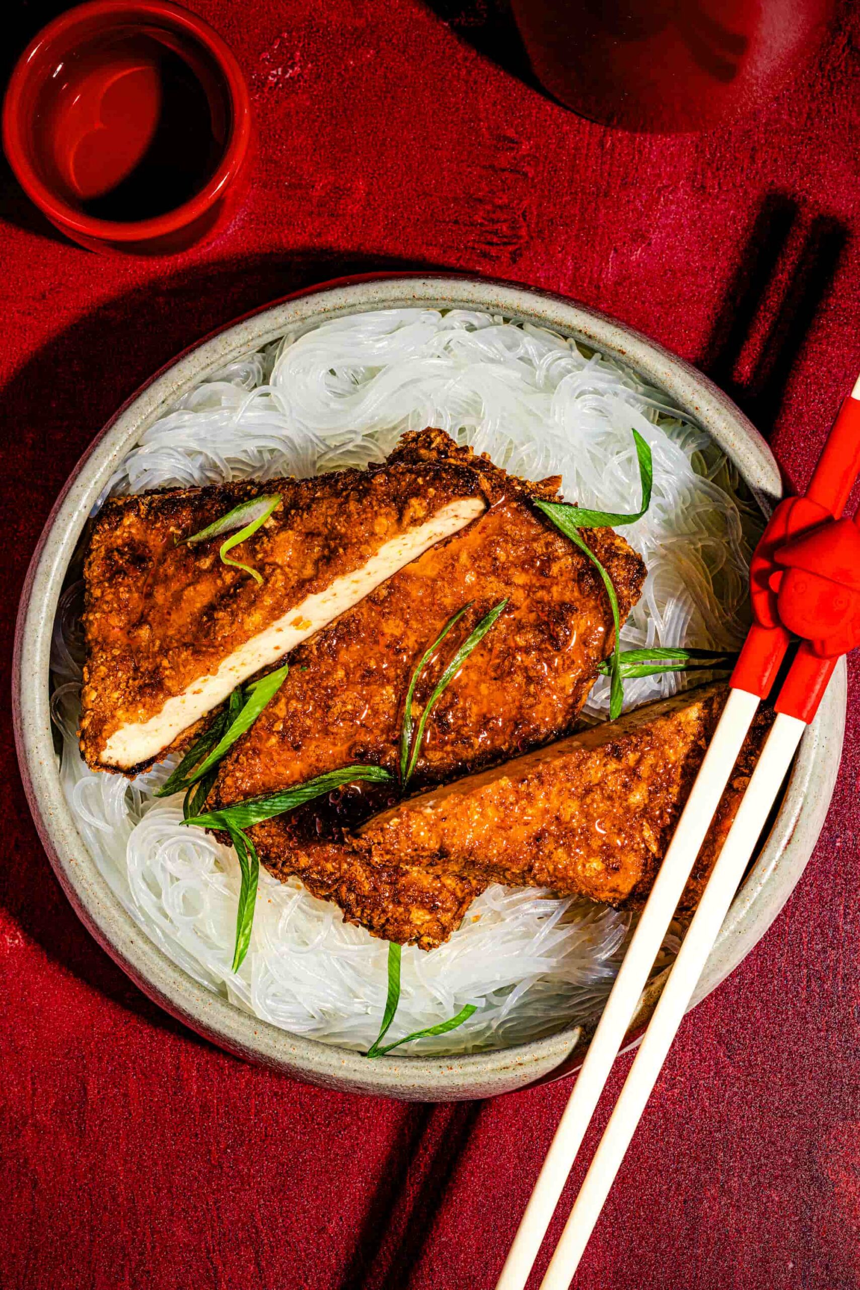 Tranches de tofu asiatique croustillant au miel épicé garnies d’oignons verts et de sésame