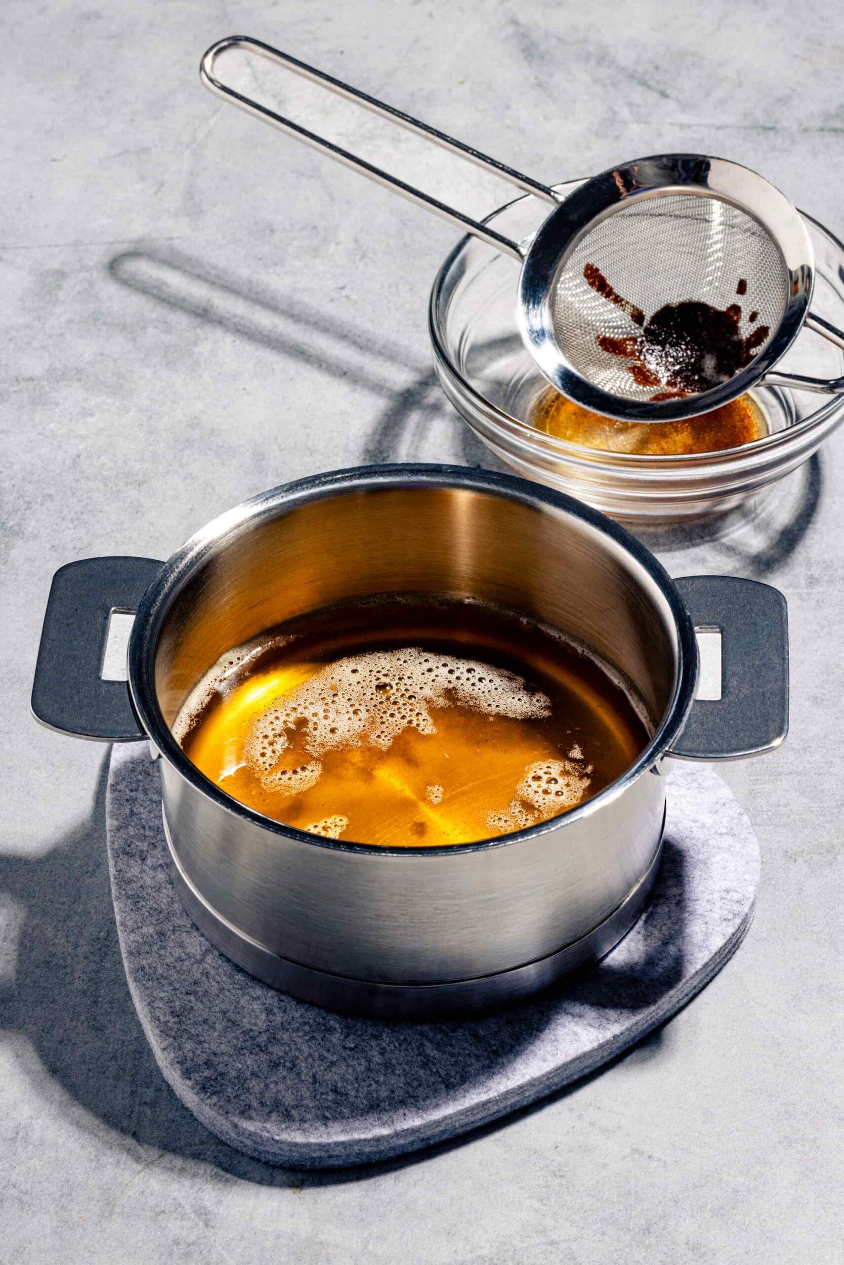 Beurre noisette maison doré dans une casserole pâle avec ses dépôts grillés