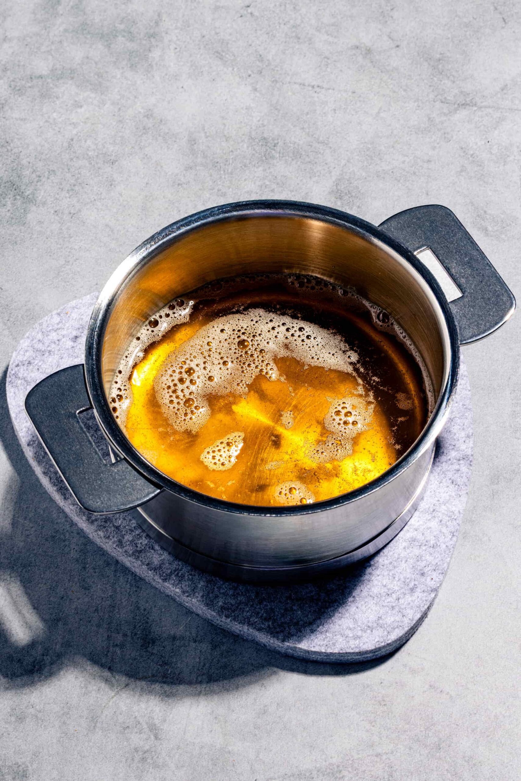 Beurre noisette maison doré dans une casserole pâle avec ses dépôts grillés