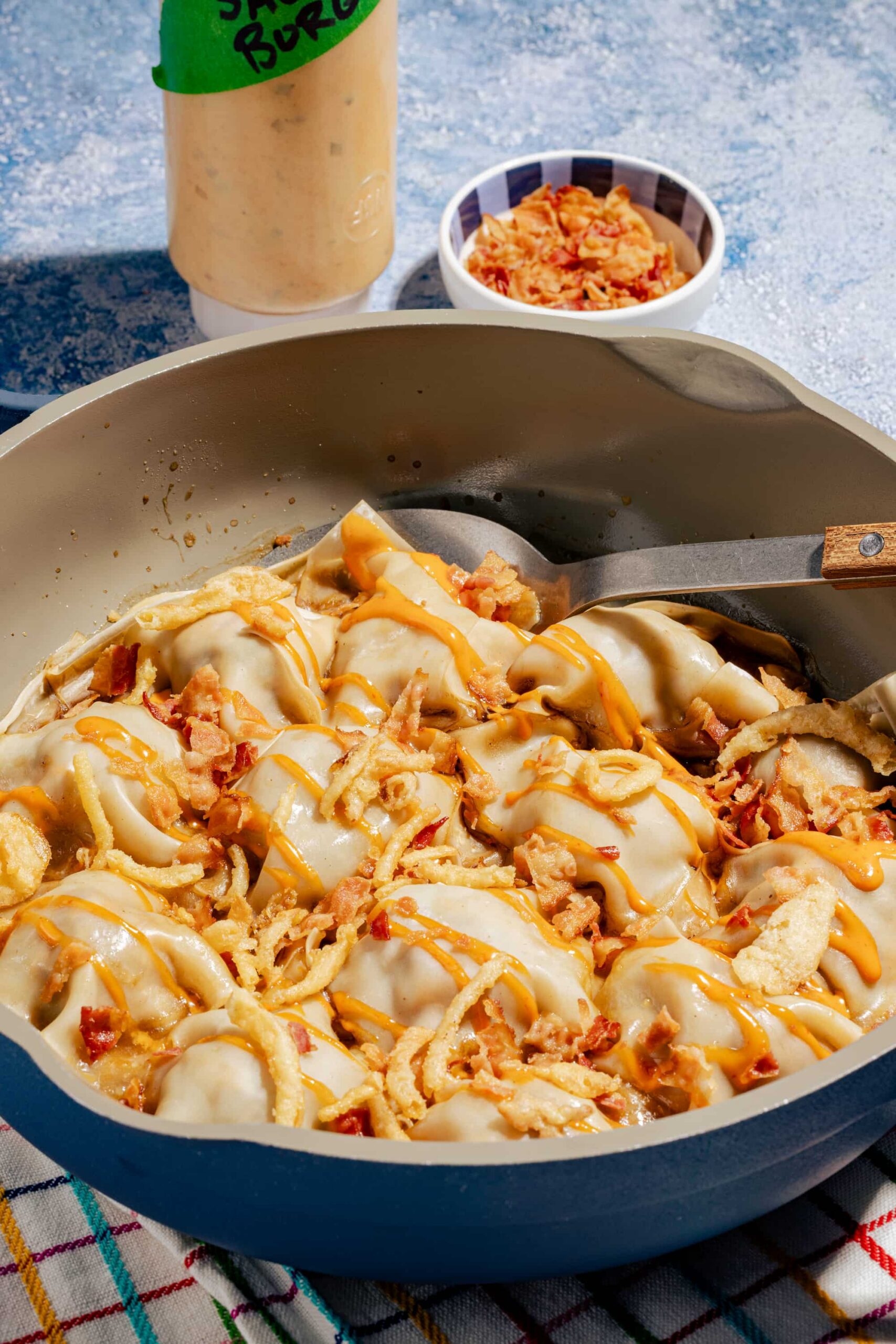 Dumplings rapides à la poêle façon cheeseburger, dorés et garnis de bœuf haché et de fromage fondant, servis dans une poêle bleue.