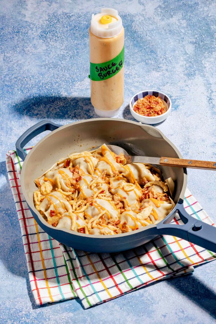 Dumplings rapides à la poêle façon cheeseburger, dorés et garnis de bœuf haché et de fromage fondant, servis dans une poêle bleue.