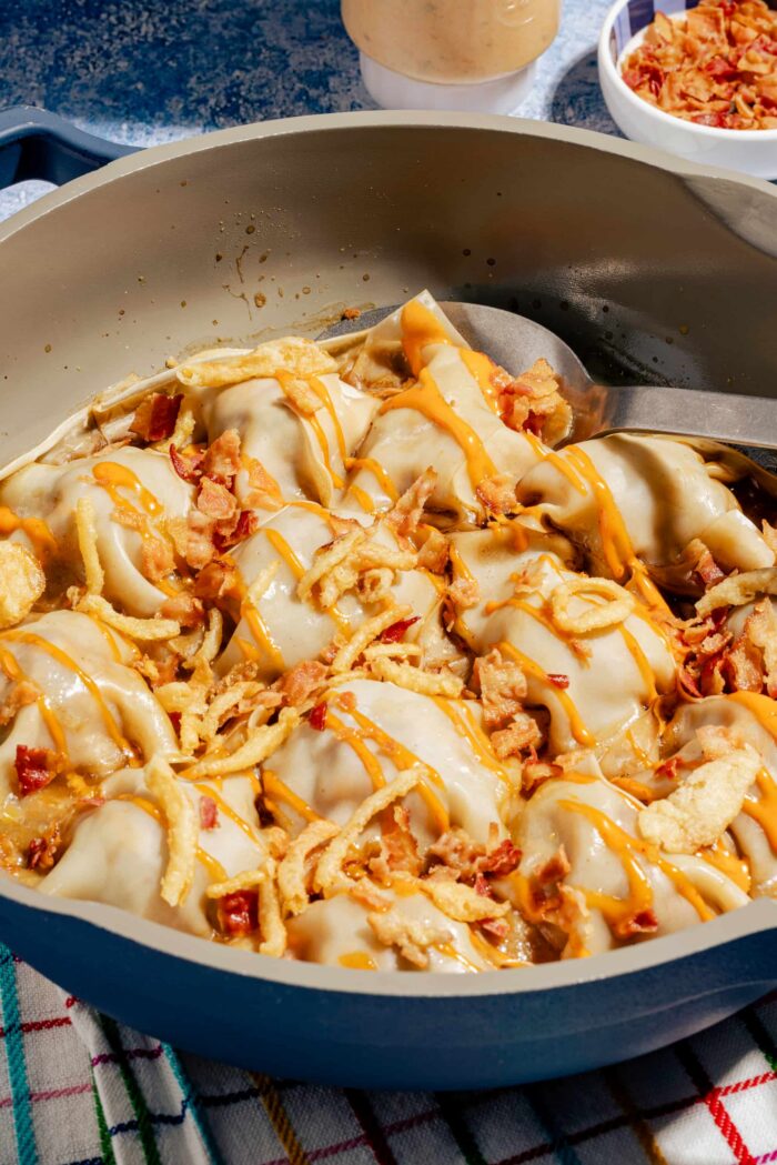 Dumplings rapides à la poêle façon cheeseburger, dorés et garnis de bœuf haché et de fromage fondant, servis dans une poêle bleue.