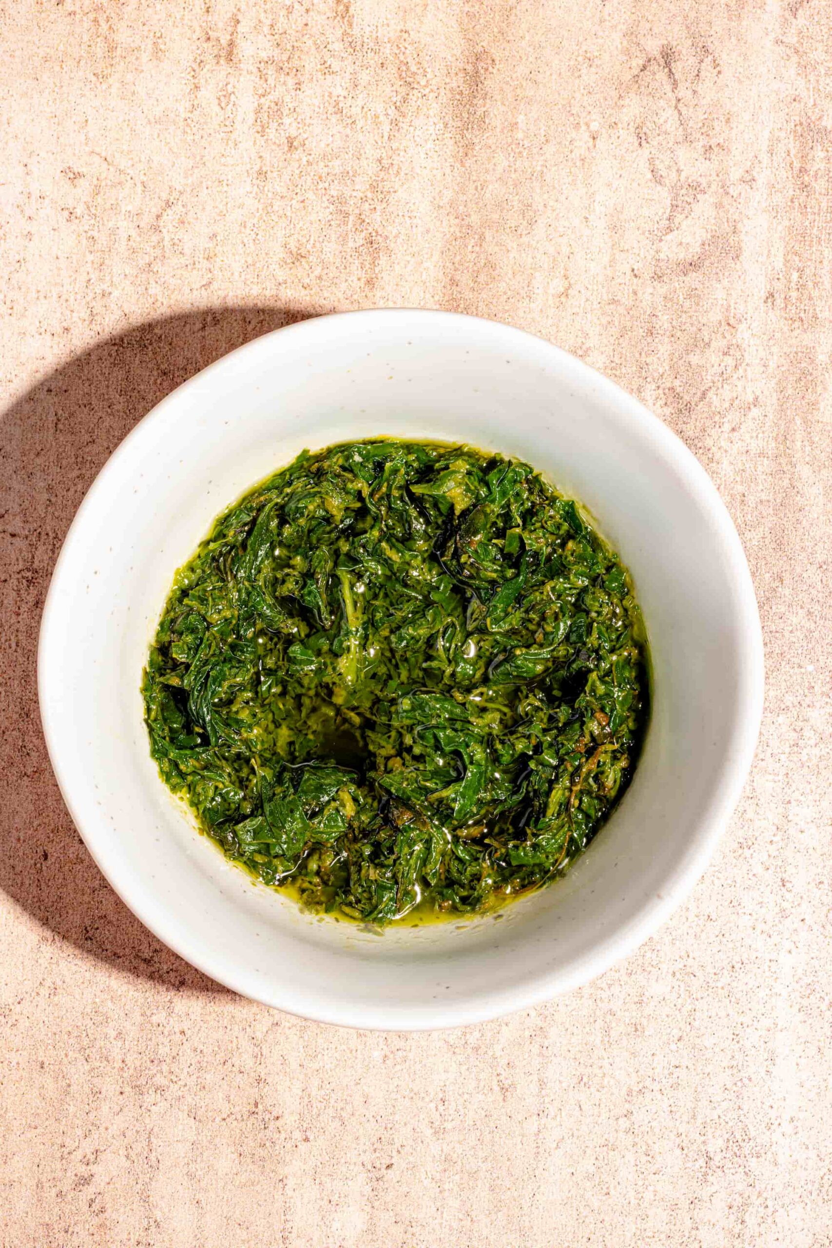 Recette maison de pistou de basilic dans un petit bol blanc